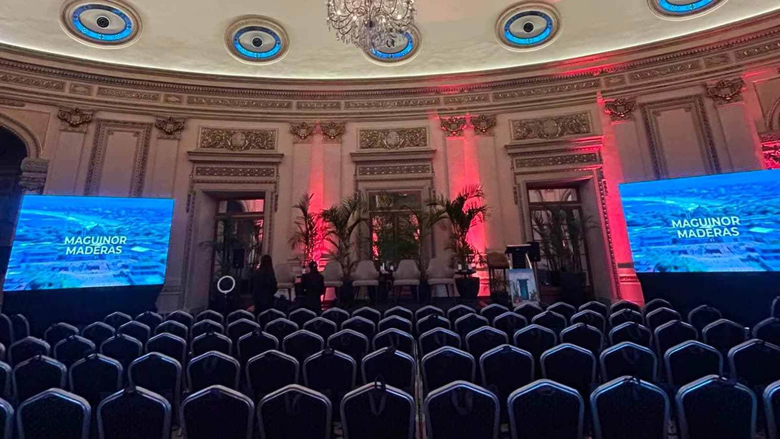 Salón histórico montado con dos pantallas LED encendidas y las paredes iluminadas en rojo